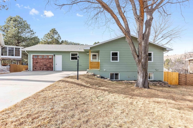 ranch-style house featuring an attached garage, fence, and driveway