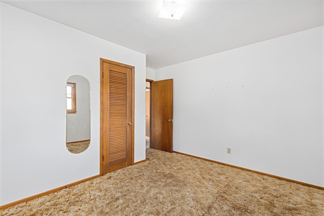 unfurnished bedroom with a closet, baseboards, and carpet flooring