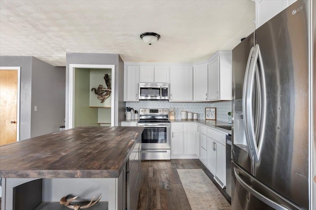 kitchen featuring butcher block countertops, a kitchen island, dark wood-style floors, stainless steel appliances, and decorative backsplash