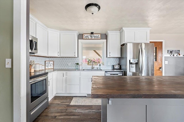 kitchen with a sink, tasteful backsplash, stainless steel appliances, white cabinets, and wooden counters