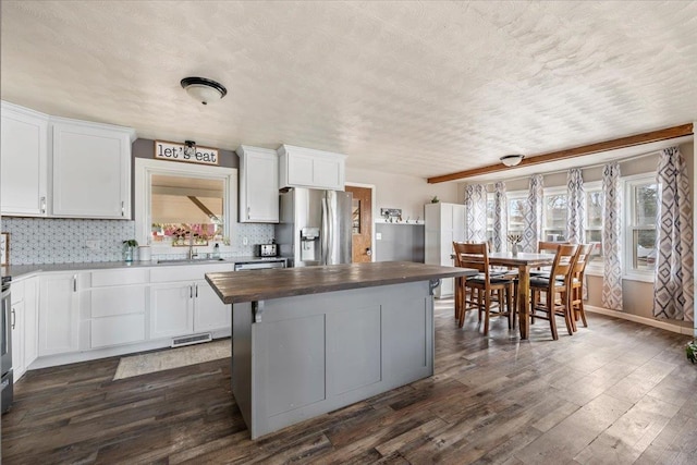 kitchen featuring wooden counters, dark wood-type flooring, decorative backsplash, stainless steel fridge, and a sink