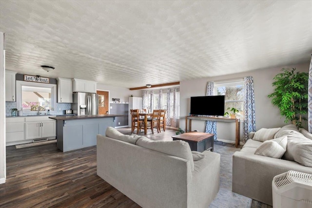 living area with plenty of natural light, a textured ceiling, and dark wood-style floors