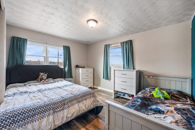 bedroom featuring a textured ceiling, baseboards, and wood finished floors