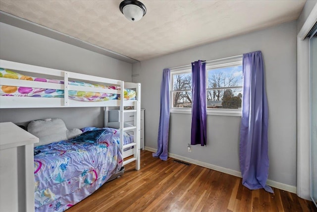 bedroom with visible vents, baseboards, and wood finished floors