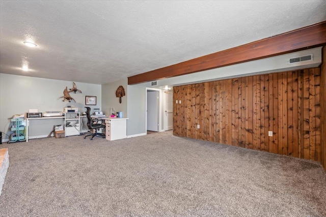 interior space with wooden walls, visible vents, carpet floors, and a textured ceiling