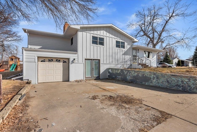 view of side of property featuring a chimney, board and batten siding, driveway, and a playground