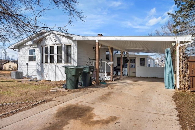 back of house featuring an attached carport, central AC, and driveway