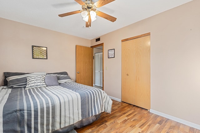 bedroom with visible vents, baseboards, ceiling fan, light wood-style floors, and a closet