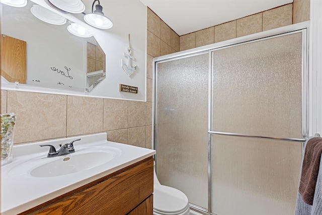 bathroom with toilet, a stall shower, tile walls, and vanity