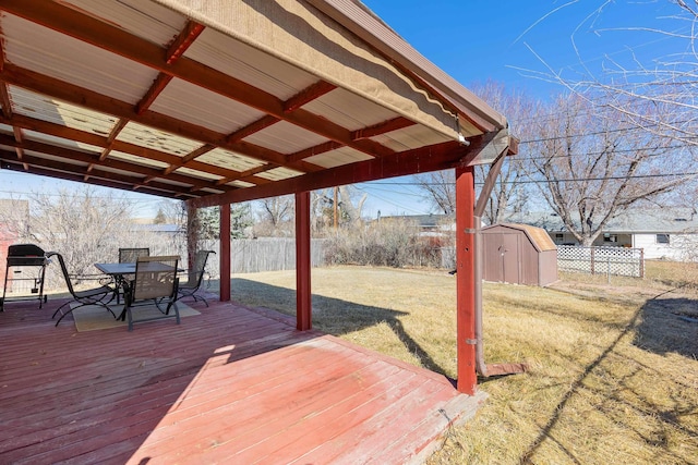 wooden terrace featuring a fenced backyard, a yard, a storage shed, an outdoor structure, and outdoor dining area