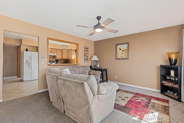 living area with light tile patterned floors, baseboards, light colored carpet, and a ceiling fan