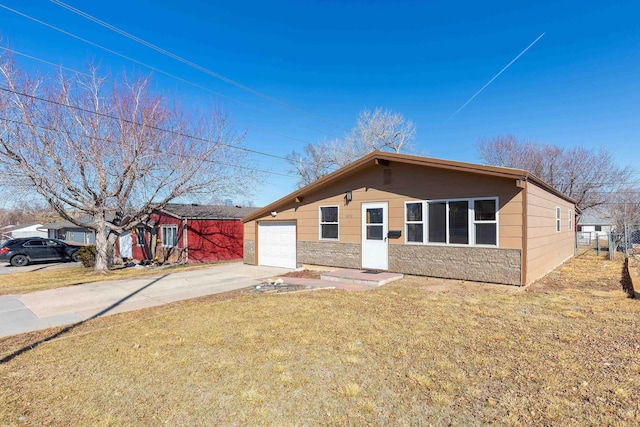 view of front of property featuring fence, concrete driveway, a front yard, stone siding, and an attached garage