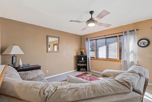 living room with a textured ceiling, carpet, baseboards, and ceiling fan