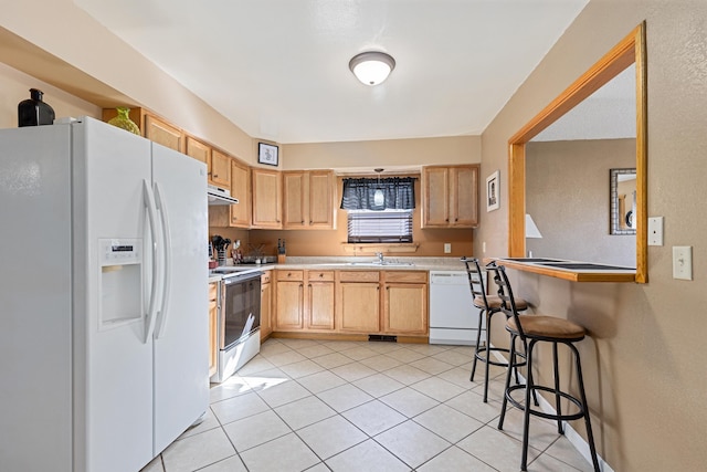 kitchen with light brown cabinets, light countertops, light tile patterned floors, white appliances, and a sink