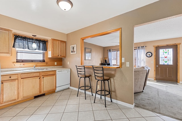 kitchen featuring a sink, dishwasher, light tile patterned flooring, and light brown cabinetry