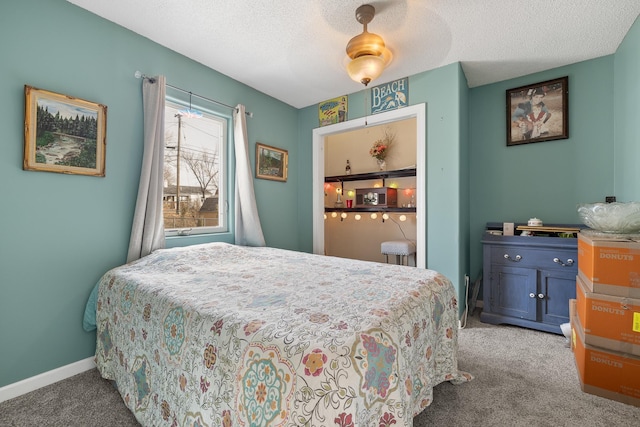 carpeted bedroom with a textured ceiling, baseboards, and a ceiling fan