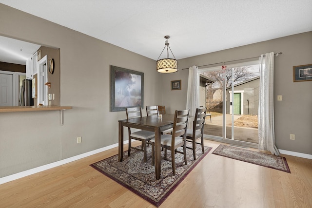 dining space with light wood-style flooring and baseboards