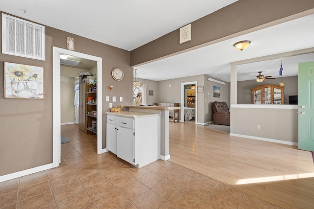 kitchen with light tile patterned floors, visible vents, ceiling fan, light countertops, and white cabinets