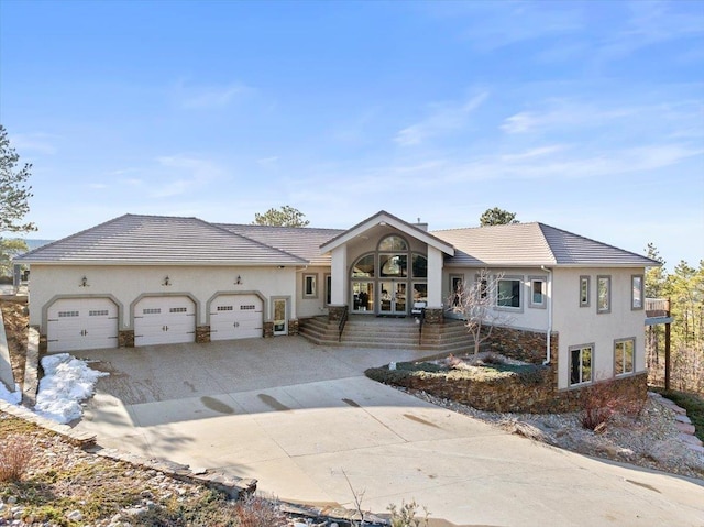 view of front of home with driveway, an attached garage, stucco siding, french doors, and a tiled roof