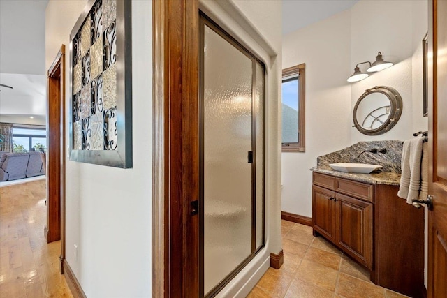 bathroom featuring vanity, baseboards, and a stall shower