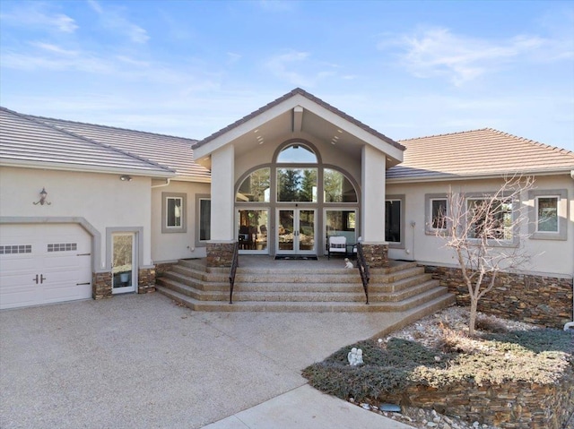 exterior space with french doors, stone siding, stucco siding, and a tiled roof