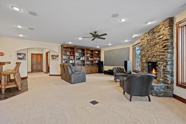 carpeted living room featuring arched walkways, recessed lighting, a fireplace, and ceiling fan