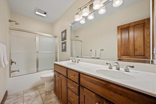 full bathroom with a sink, bath / shower combo with glass door, toilet, and double vanity