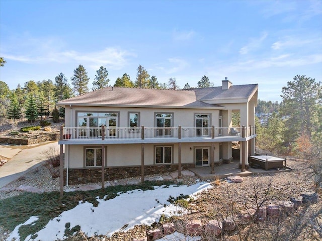 back of house featuring a patio area, stucco siding, a chimney, and a deck