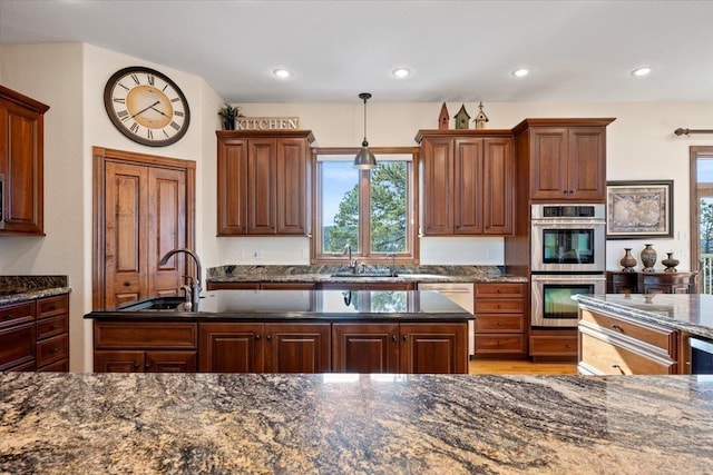 kitchen with pendant lighting, dark stone counters, recessed lighting, stainless steel appliances, and a sink