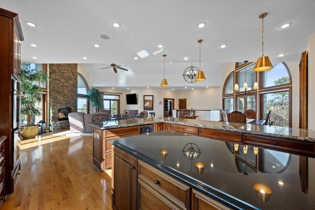 kitchen featuring a stone fireplace, recessed lighting, wood finished floors, and open floor plan