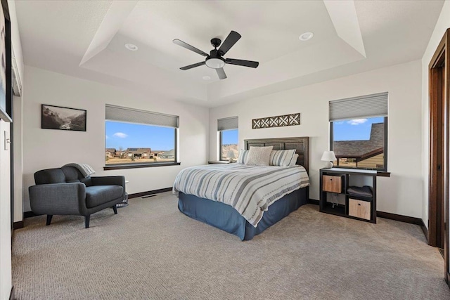 carpeted bedroom with a tray ceiling, baseboards, and ceiling fan