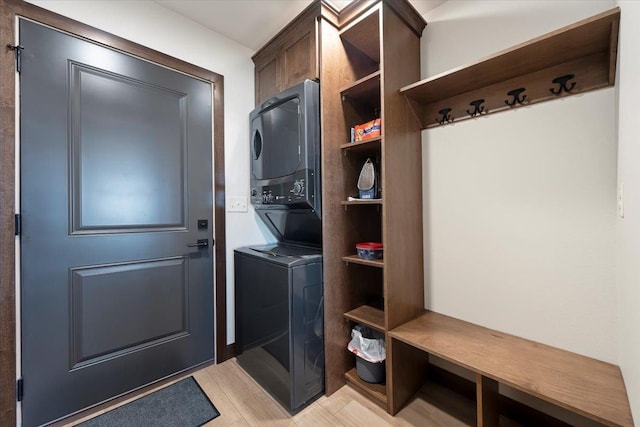 washroom with cabinet space, stacked washer and dryer, and light wood-style flooring