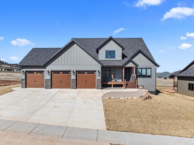 view of front facade featuring driveway, stone siding, board and batten siding, covered porch, and a garage