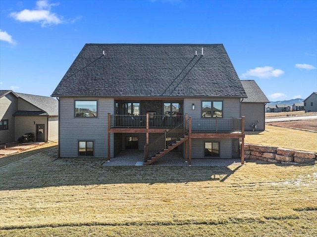 back of house with a deck, stairway, a yard, and a shingled roof