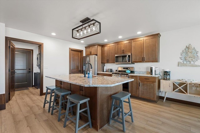 kitchen with recessed lighting, light wood-style flooring, appliances with stainless steel finishes, and a breakfast bar area