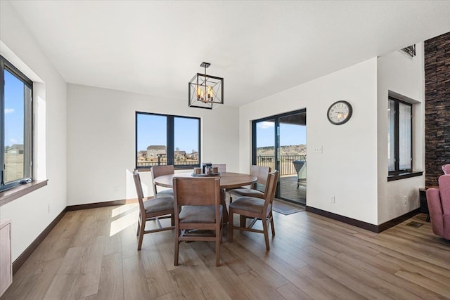 dining area with baseboards, a chandelier, and light wood finished floors