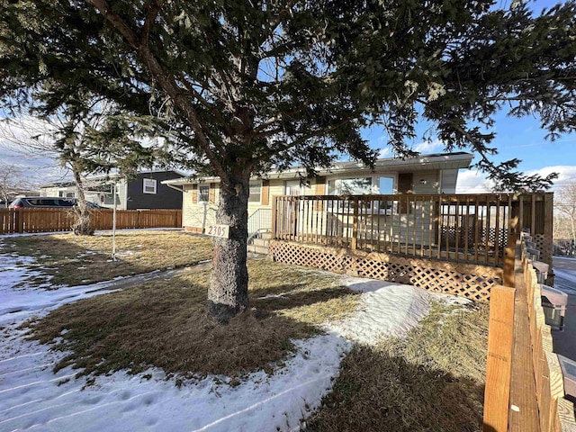 snowy yard with a deck and fence