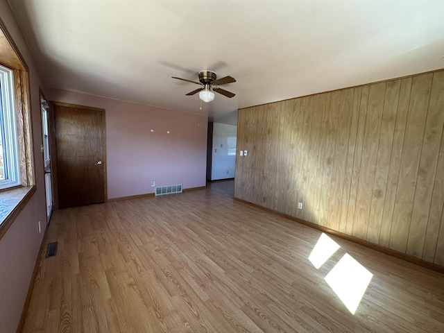 spare room featuring light wood finished floors, visible vents, baseboards, and ceiling fan