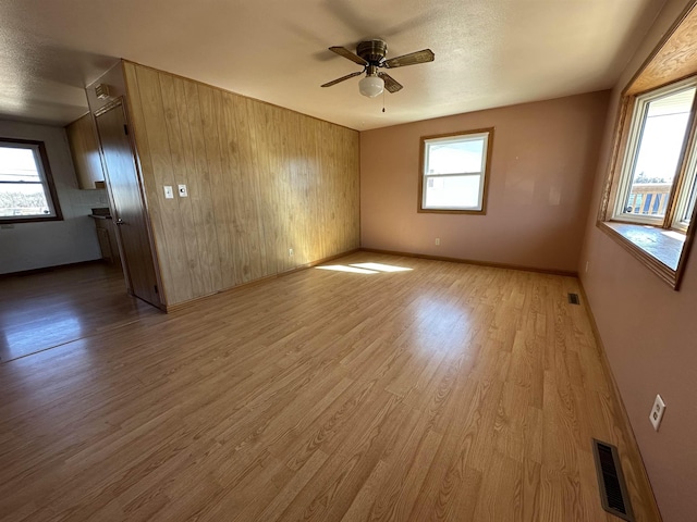 unfurnished room with ceiling fan, visible vents, baseboards, and wood finished floors