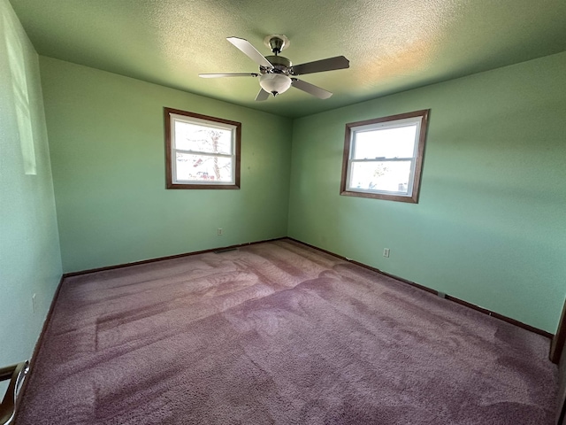 carpeted empty room with a textured ceiling, a healthy amount of sunlight, and ceiling fan