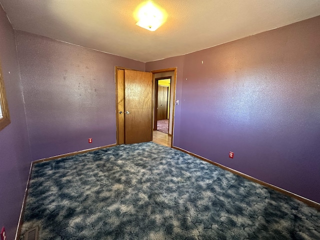 carpeted spare room featuring baseboards