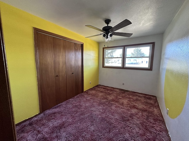 unfurnished bedroom with a textured ceiling, a closet, carpet floors, and ceiling fan