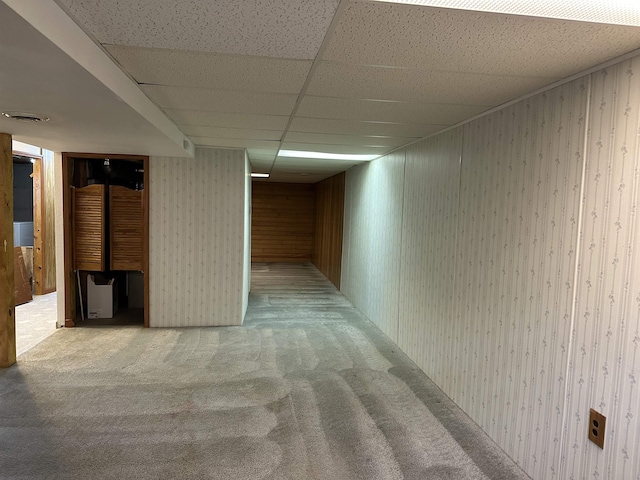 finished basement with light carpet, visible vents, and a paneled ceiling