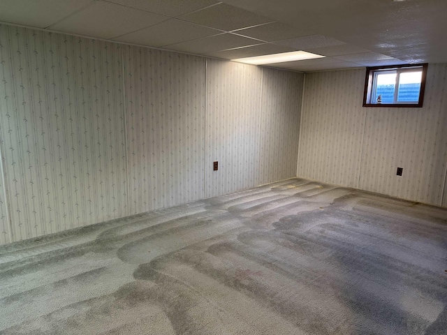 basement with a paneled ceiling and carpet