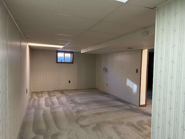 below grade area with carpet flooring and a paneled ceiling