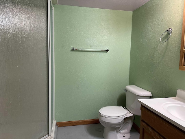 bathroom featuring vanity, a shower stall, toilet, and baseboards