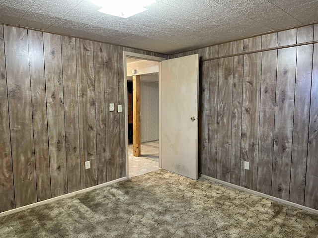 spare room featuring wooden walls and carpet