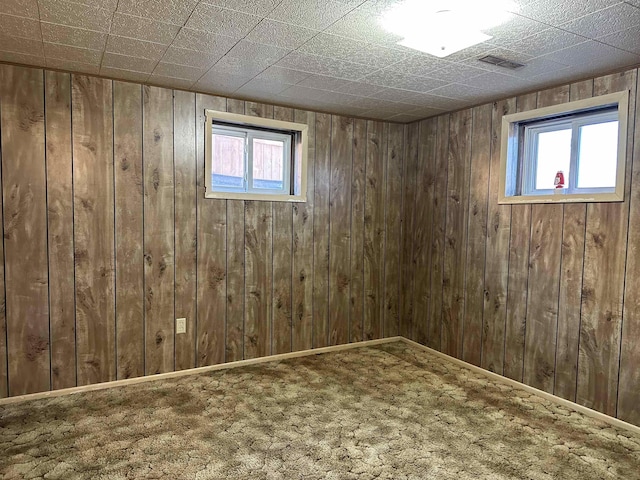 below grade area featuring visible vents, baseboards, carpet, and wooden walls