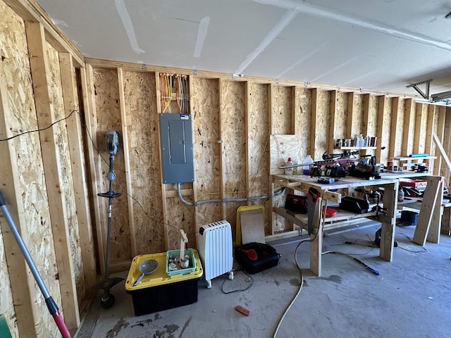 misc room with a workshop area, electric panel, and radiator heating unit