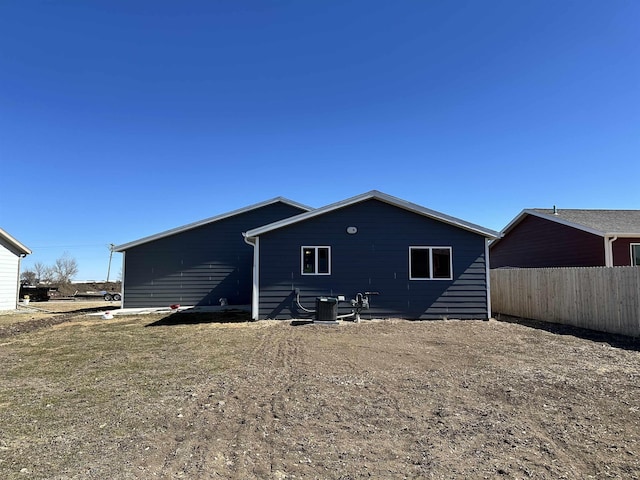 rear view of house featuring central air condition unit and fence